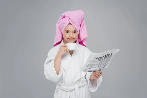 Femme avec syndrome duvet en peignoir tenant tasse et journal isolé sur gris — Photo de stock