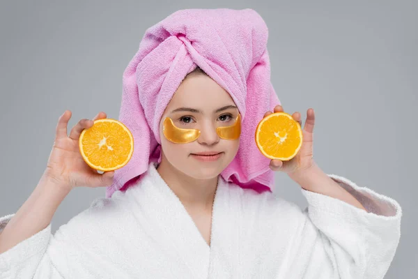 Woman with down syndrome in eye patches holding orange isolated on grey — Stock Photo