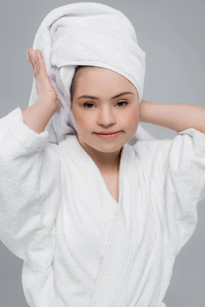 Mulher com síndrome de down em roupão de banho segurando toalha na cabeça isolada em cinza — Fotografia de Stock