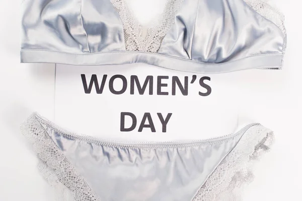 Vista superior do cartão com letras do dia das mulheres perto de lingerie no fundo branco — Fotografia de Stock