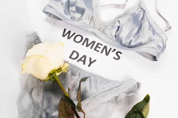 Top view of card with womens day lettering, rose and lingerie on white background — Stock Photo