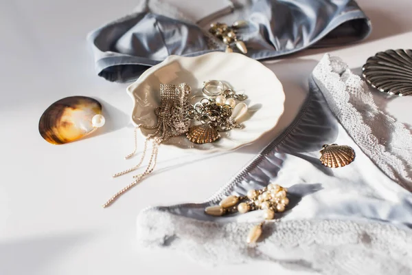 Vista de cerca de accesorios cerca de conchas y lencería sobre fondo blanco - foto de stock