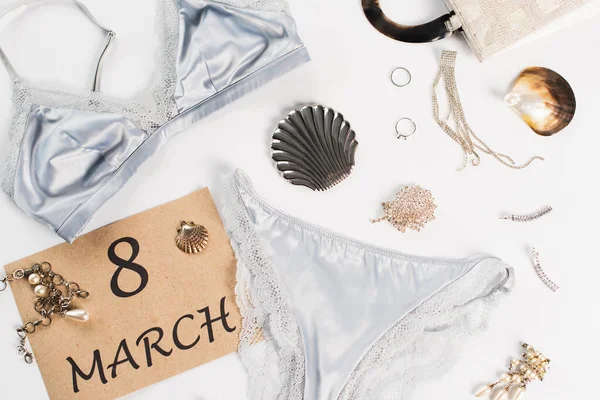 Vue du dessus de lingerie près du sac et de la carte avec lettrage 8 mars sur fond blanc — Photo de stock