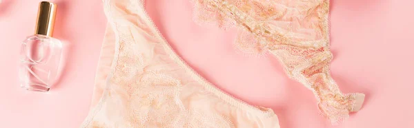 Top view of peach lingerie near perfume on pink background, banner — Stock Photo