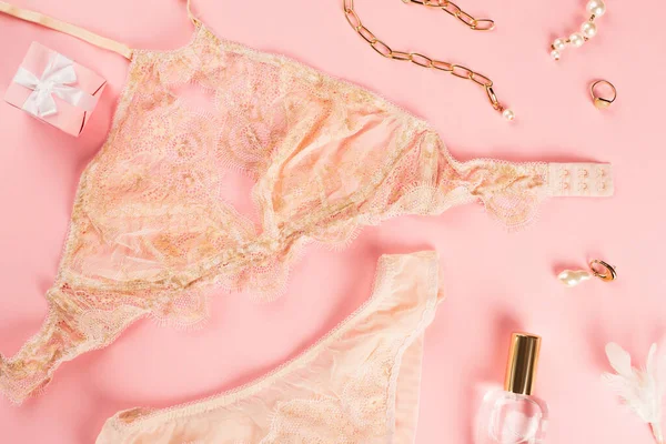 Vista dall'alto di lingerie vicino presente e bottiglia di profumo su sfondo rosa — Foto stock