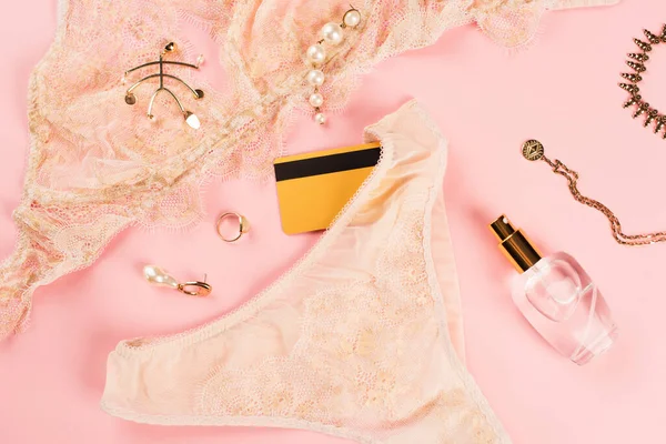 Vue du dessus de la carte de crédit près de lingerie et bouteille de parfum sur fond rose — Photo de stock