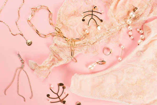 Top view of golden accessories on lace underwear on pink background — Stock Photo