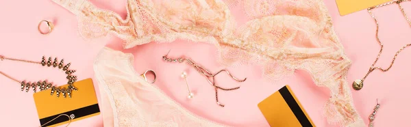 Вид сверху кредитных карт, кружевное белье и золотые аксессуары на розовом фоне, баннер — стоковое фото