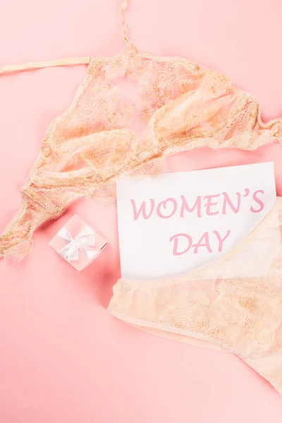 Top view of underwear, present and card with womens day lettering on pink background — Stock Photo