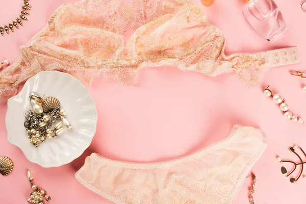 Vista dall'alto di lingerie di pizzo, profumo e accessori su sfondo rosa — Foto stock