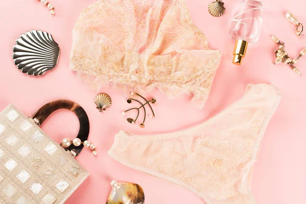 Top view of lingerie near perfume and bag on pink background — Stock Photo