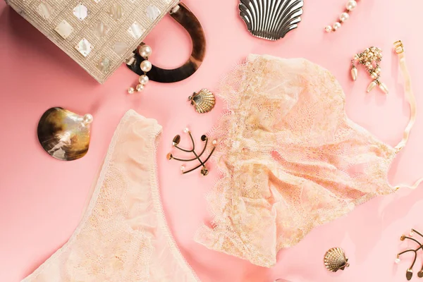Vista superior de lingerie rendas perto de acessórios dourados e saco no fundo rosa — Fotografia de Stock