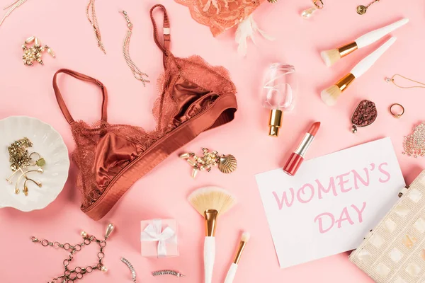 Vista superior do sutiã, cartão com letras do dia das mulheres, presente e perfume sobre fundo rosa — Fotografia de Stock