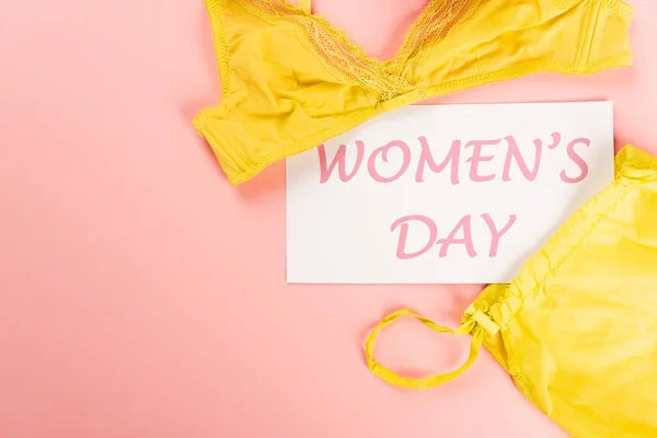 Top view of card with womens day lettering near bra on pink background — Stock Photo