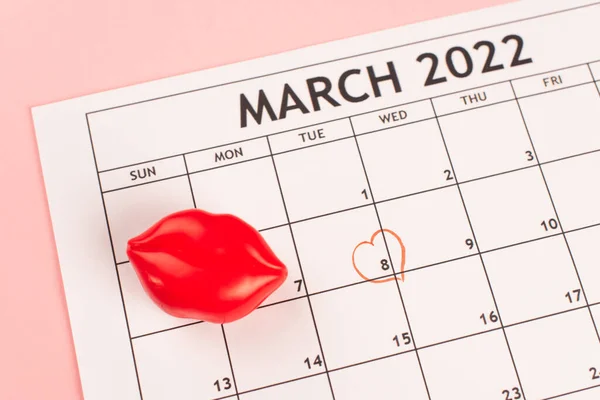 Vista superior del calendario de marzo con el signo del corazón sobre fondo rosa - foto de stock