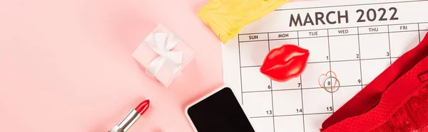 Vue du dessus du calendrier de mars près de lingerie, cadeau et téléphone portable sur fond rose, bannière — Photo de stock
