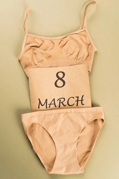 Top view of beige cotton underwear and card with 8 march lettering on green background — Stock Photo