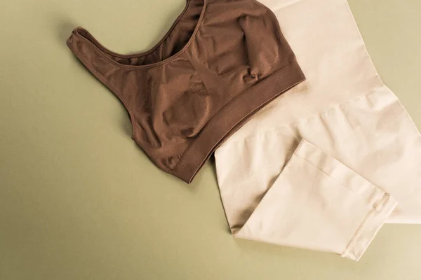 Top view of brown bra and cotton control briefs on green background — Stock Photo