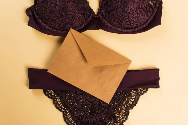 Top view of envelope and lace lingerie on beige background — Stock Photo