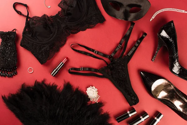 Top view of sexy lingerie, lipsticks and heels on red background — Stock Photo