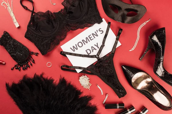 Top view of card with womens day lettering near sexy lingerie, heels and accessories on red background — Stock Photo