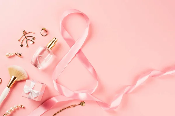 Draufsicht auf Parfüm, Accessoires und Band in Form von 8 Zeichen auf rosa Hintergrund — Stockfoto