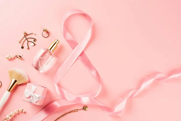 Vue du dessus du parfum, des accessoires et du ruban en forme de 8 signes sur fond rose — Photo de stock