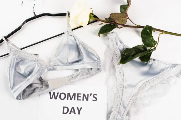 Top view of lingerie near card with womens day lettering and rose on white background — Stock Photo