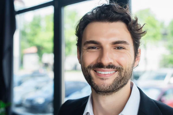 Portrait of cheerful brunette businessman looking at camera in office — Stock Photo