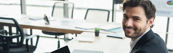 Happy businessman looking at camera in blurred office, banner — Stock Photo