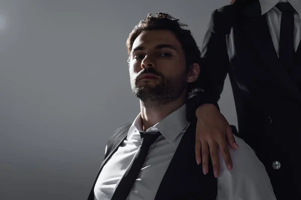 Brunette man in white shirt and black tie looking at camera near woman isolated on grey — Stock Photo