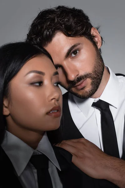 Elegante uomo guardando fotocamera vicino bella asiatico donna isolato su grigio — Foto stock