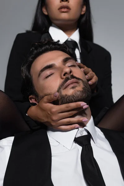 Чоловік із закритими очима біля сексуальної жінки спокушає його на розмитому фоні ізольовано на сірому — стокове фото