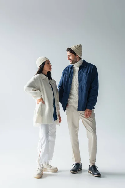 Full length view of stylish interracial couple looking at each other on grey — Stock Photo