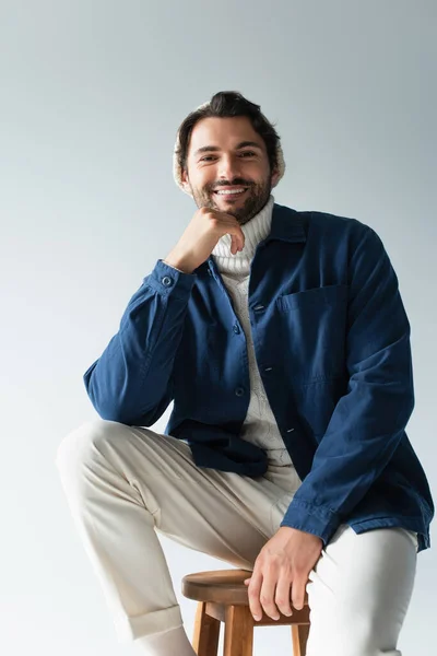 Cheerful man in white trousers and blue jacket looking at camera isolated on grey — Stock Photo