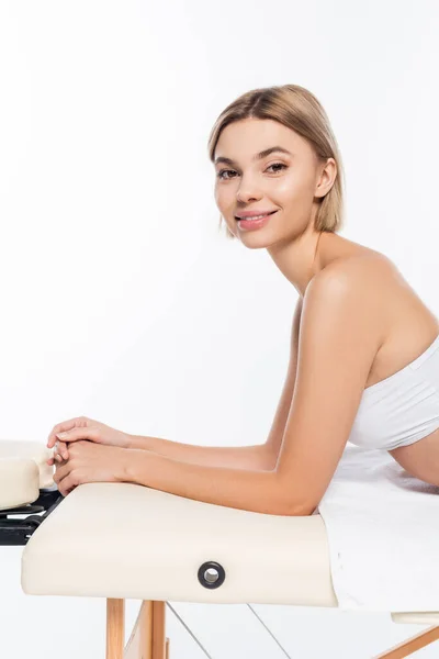 Happy young woman in crop top lying on massage table isolated on white — Stock Photo