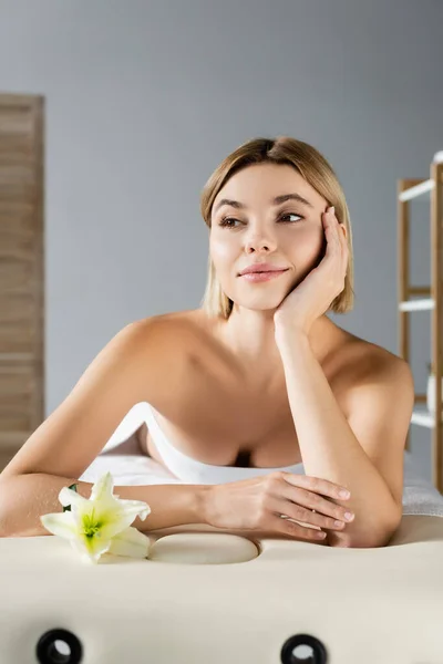 Young blonde woman lying on massage table near flower — Stock Photo