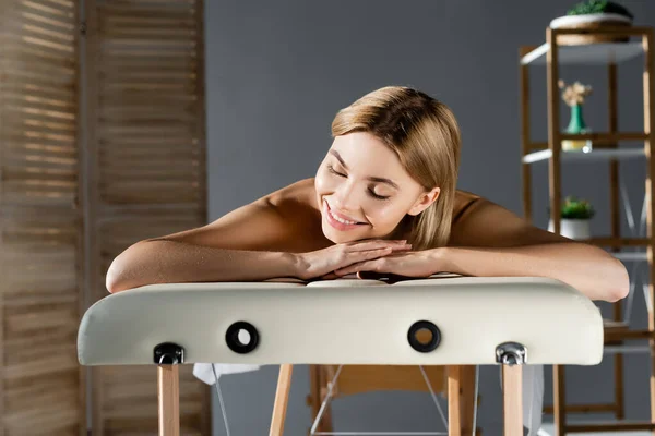 Alegre joven mujer acostada en la mesa de masaje - foto de stock