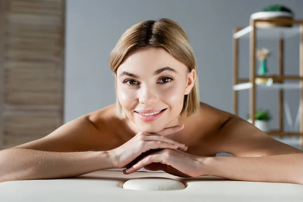 Jovencita alegre tumbada en la mesa de masaje - foto de stock