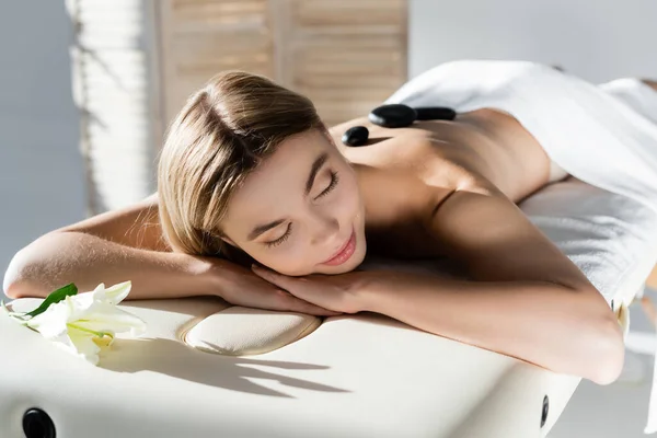 Blonde young woman receiving hot stone massage — Stock Photo