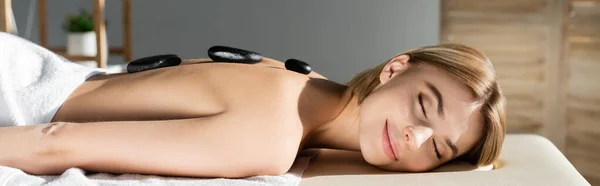 Happy young woman receiving hot stone massage, banner — Stock Photo