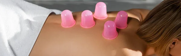 Vue recadrée de la jeune femme avec des tasses de massage rose sur le dos recevant massage sous vide, bannière — Photo de stock