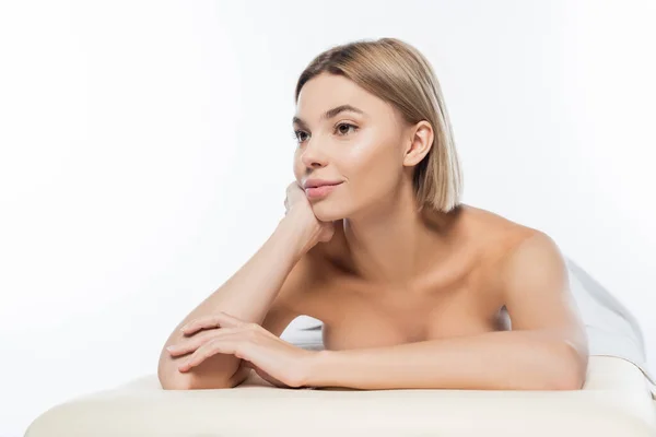 Dreamy woman with bare shoulders lying on massage table on white — Stock Photo