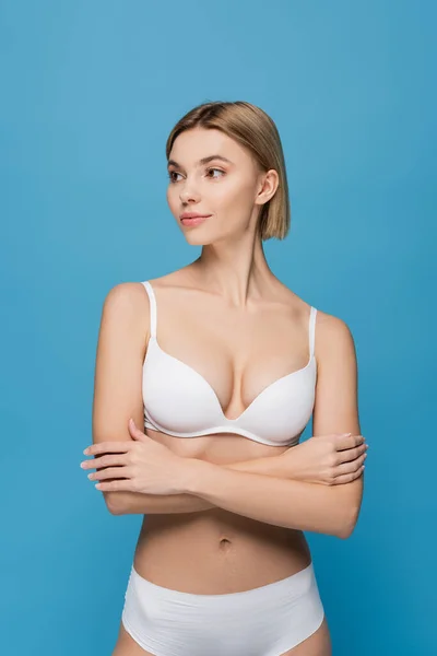 Slim young woman in white underwear looking away isolated on blue — Stock Photo