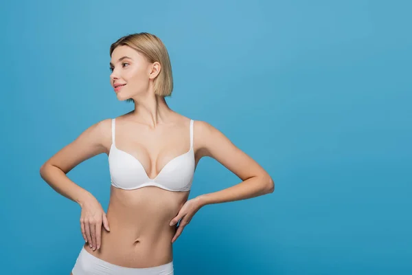 Slim jeune femme en lingerie blanche toucher le corps isolé sur bleu — Photo de stock