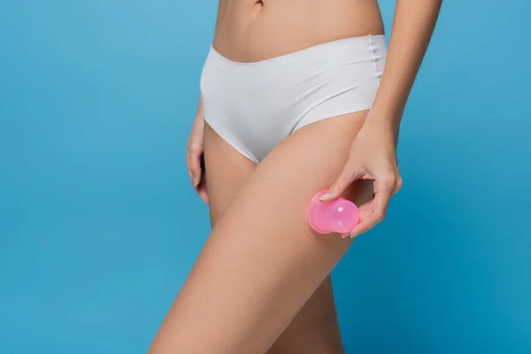 Corte vista de mulher em calcinha segurando copo de massagem isolado em azul — Fotografia de Stock