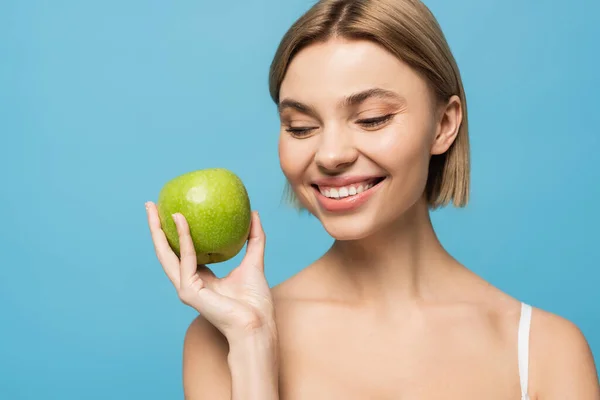 Allegra giovane donna che tiene mela verde matura isolata su blu — Foto stock