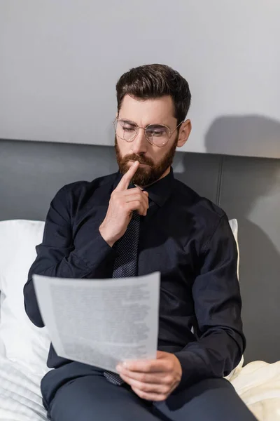 Uomo premuroso negli occhiali guardando il documento in hotel — Foto stock