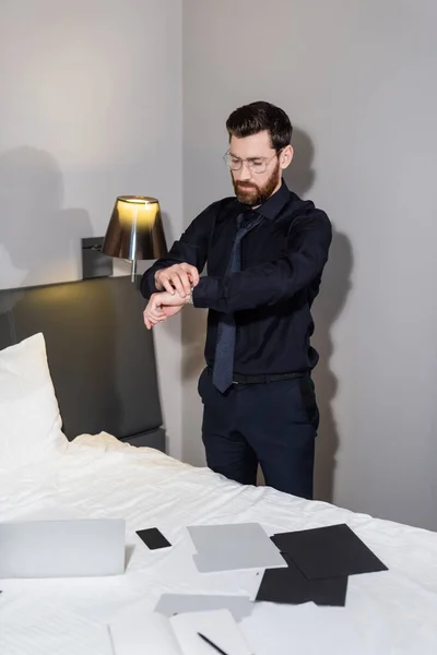 Homem barbudo em óculos ajustando relógio de pulso no hotel — Fotografia de Stock
