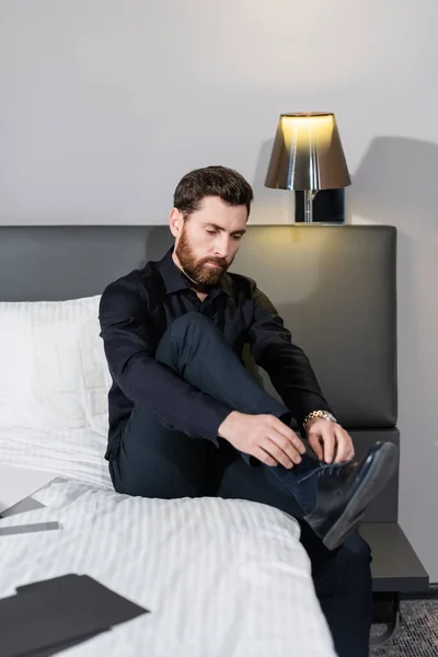 Bearded man tying laces on shoes in hotel — Stock Photo